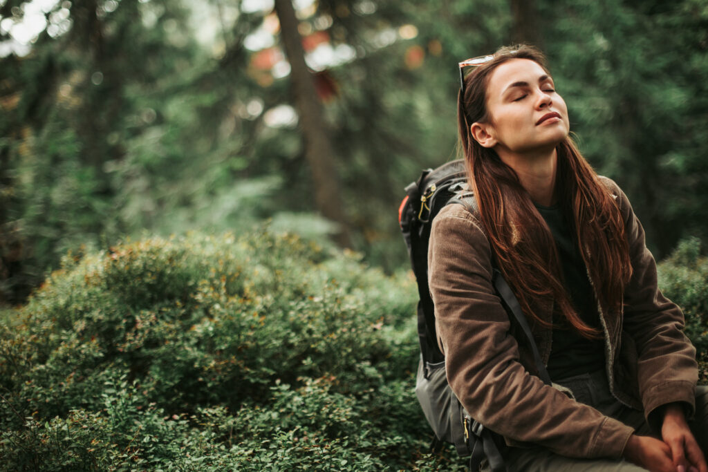 Woman meditating in green nature practicing self-care