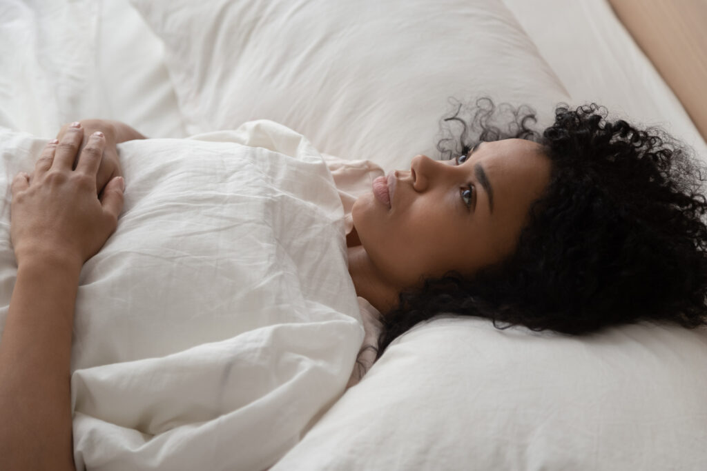 woman awake in bed feeling anxious with self-doubt