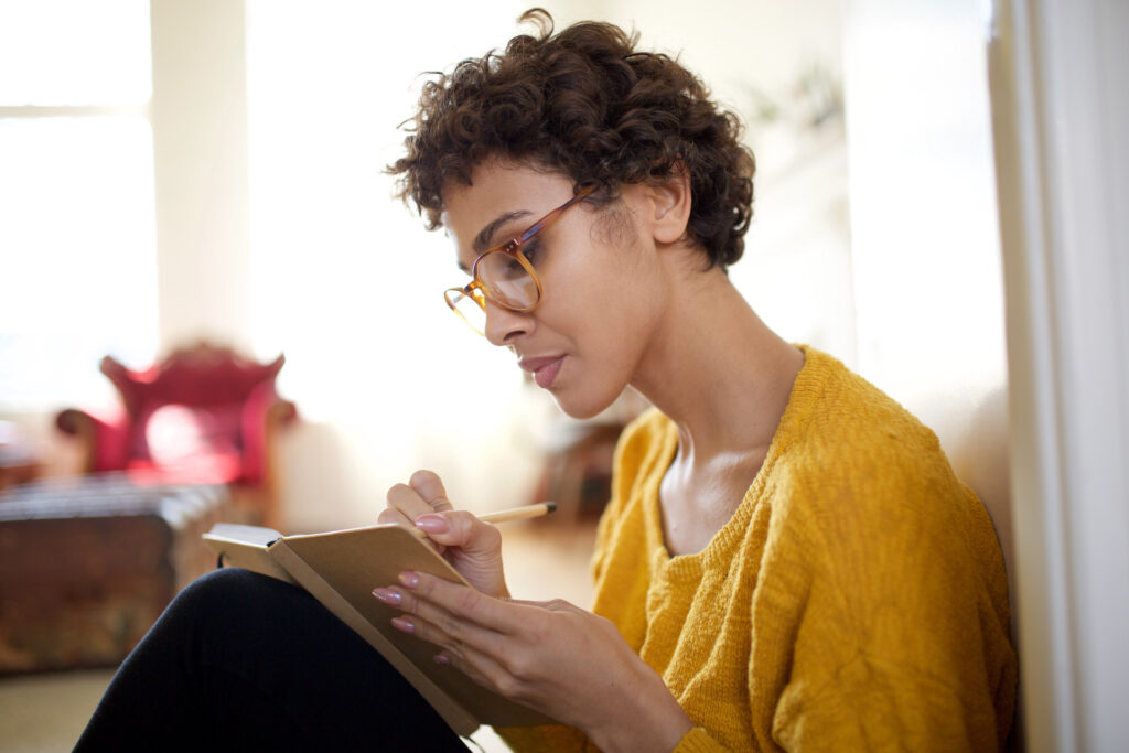 Young woman writing in her journal about how to forgive