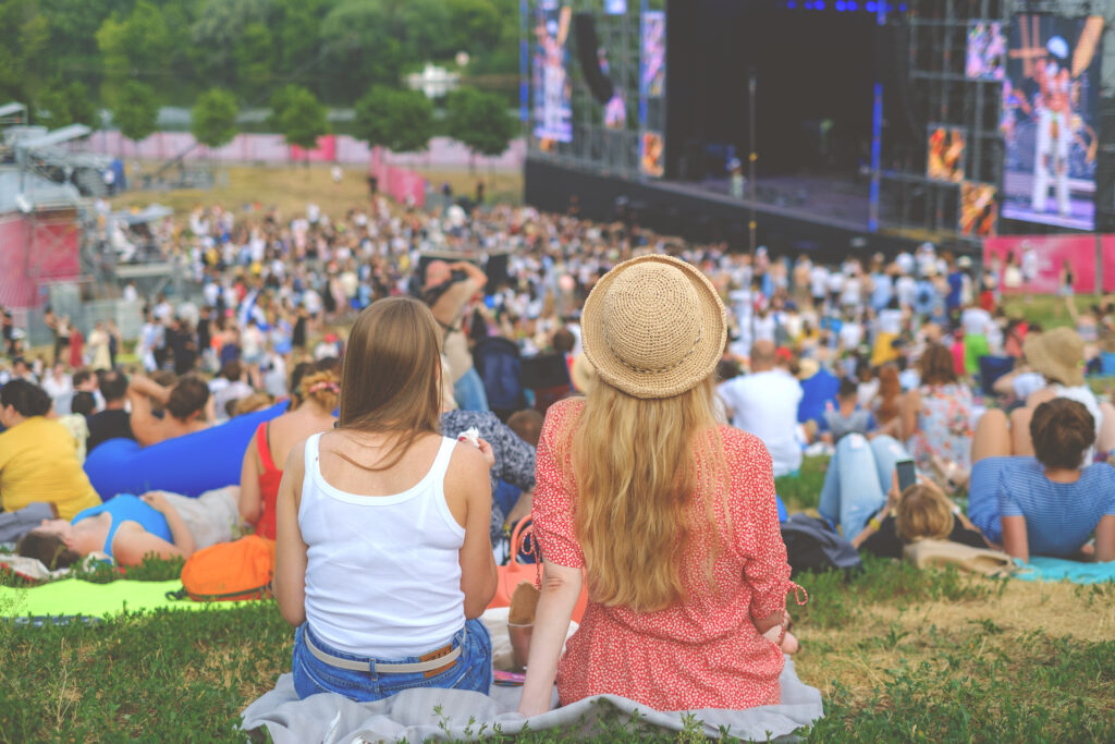 two friends sitting at an outdoor concert offering support for substance use recovery