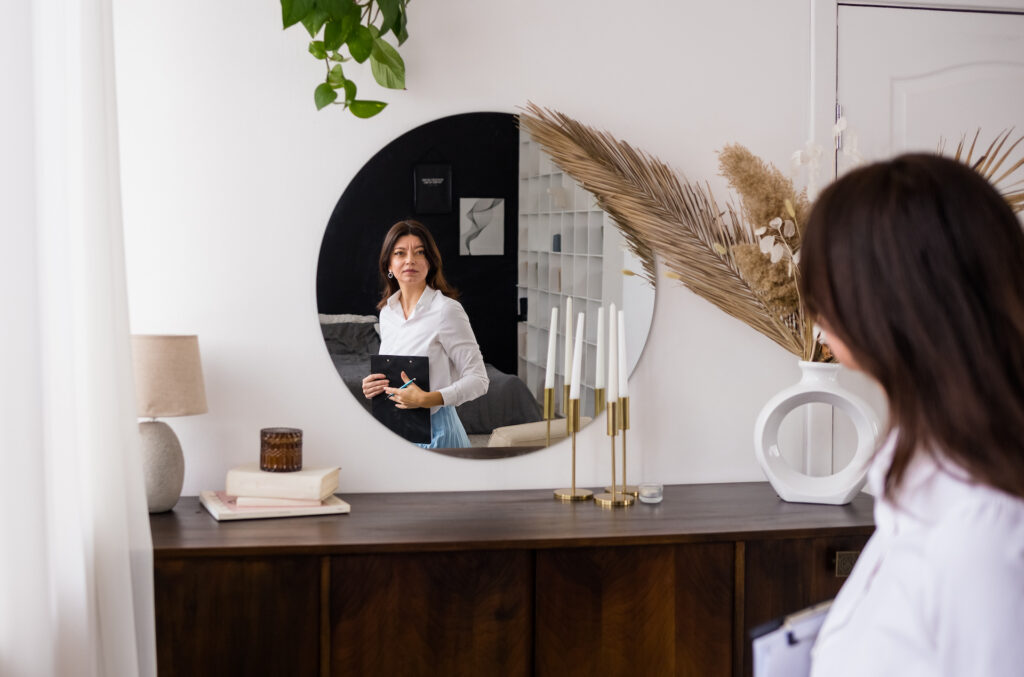 woman looking in mirror thinking about body image